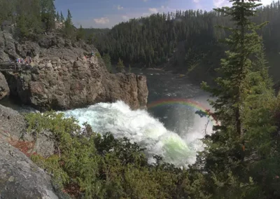 Image of waterfall in Yellowstone National Park with rainbow in mist.